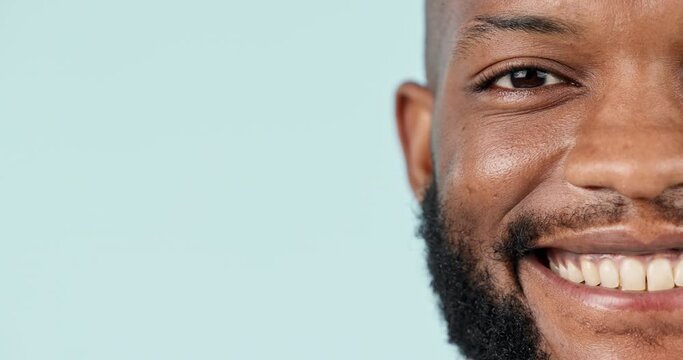 Half face, smile and mockup with a black man closeup in studio on a blue background for marketing. Portrait, space and a happy young person looking confident on an advertising backdrop for a logo