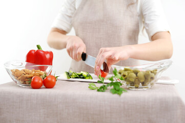 Beautiful young woman preparing vegetable salad in the kitchen. Healthy food. Vegan salad Diet concept. Healthy lifestyle. Cook at home. Prepare food close-up, only hands, olives, tomato, cucumber