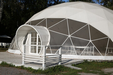 White tent for a party in the park. Dome-shaped building for weddings, holidays and outdoor weekends with transparent walls - obrazy, fototapety, plakaty