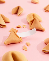 Fortune cookies on a pink background with deep long shadows. Blank paper for prediction words