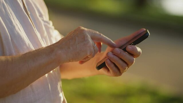 The hands of an old man are holding a mobile phone