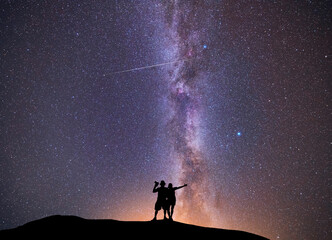 Fantasy landscape, couple in love standing on the hill, and looking at the Milky Way galaxy .