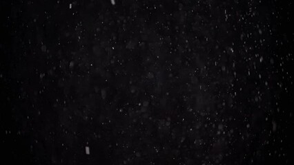 Slowly Falling Stream of Particles of Dust, Snow, Tinsel on a Black Background. White spots of powder and flakes are mixed in the empty space. Stardust. Accumulation of gas, fog. Space. Slow motion.