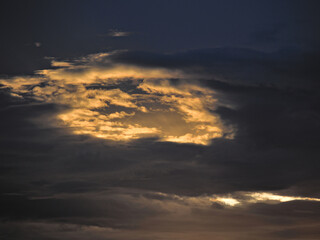 Fototapeta na wymiar shaded clouds forming a window backlit by the twilight sun.