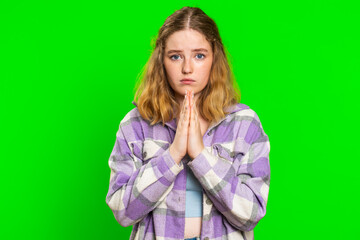 Please, God help. Caucasian woman praying looking at camera and making wish, asking with hopeful imploring expression, begging apology, meditation. Redhead girl isolated on green chroma key background