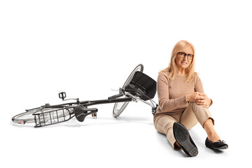 Fototapeta premium Woman in pain sitting on the floor next to a bicycle and holding her knee
