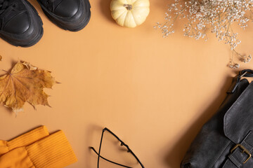 Woman's shoes with autumn leaves and pumpkin on orange background with copy space top view, flat lay