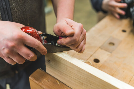 Closeup carpenter planing wood by hand with a planer . High quality photo