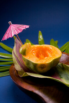Studio Shot Of Half Of A Papaya, Seeds Removed, With Cocktail Umbrella.