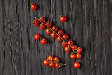 Fresh cherry tomato branches on wooden background top view.