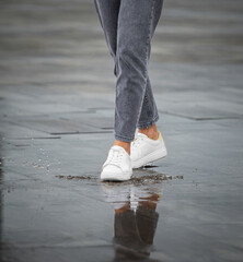 Legs of a girl in rainy weather on the street in the city