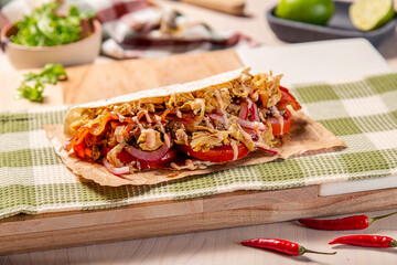 Tacos mexicanos de carnitas y tinga de pollo, sobre tabla de madera en una composición sobre mesa...