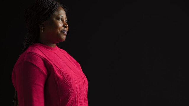 Side-view portrait of female model performing timeout, pause motion on camera. African american woman in black background displaying a t shape stop symbol with her arms, indicating no.