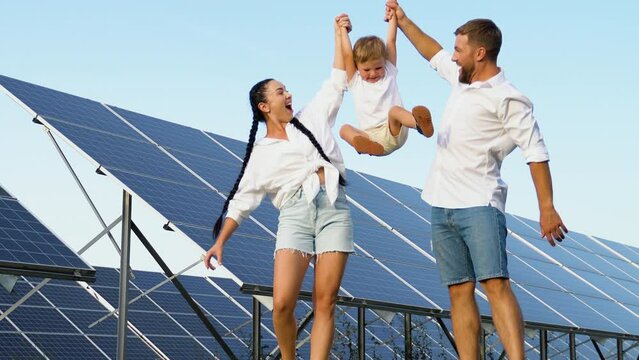 Happy family walking near solar panels, green living concept