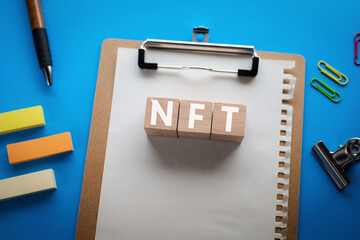 There is wood cube with the word NFT. It is an abbreviation for Non-Fungible Token as eye-catching image.