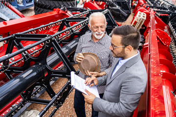 Tractor dealer selling agricultural machines and equipment to farmer. Customer buying combine...