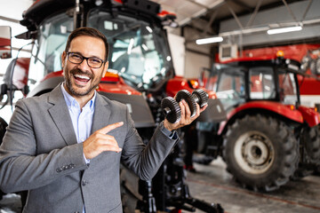 Portrait of professional tractor salesman standing at dealership showroom.