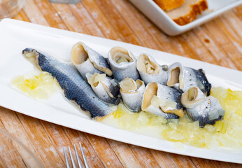 Delicious herring fillet with onion and sunflower oil, laid out on a plate. Close-up image
