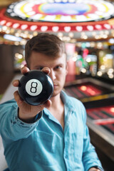 Man shows ball with number to camera. Lucky number or winning lottery. Numerology and divination. Number eight on round ball.