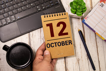 White block calendar present date 12 and month October on wood background.