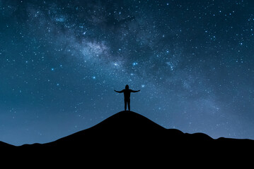 Silhouette of young traveler and backpacker raise both arms and watched the star and milky way...