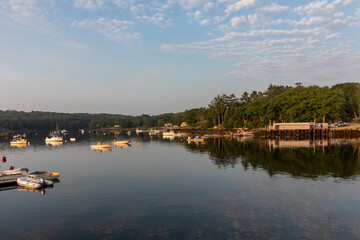 Fototapeta na wymiar Round Pond Harbor, Maine, USA, boats in the harbor on a quiet still morning at sunrise in summer