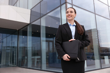 Fototapeta premium Female real estate agent with leather portfolio outdoors