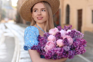 Beautiful woman with bouquet of spring flowers on city street