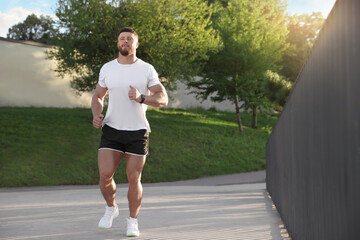 Young man running outdoors on sunny day. Space for text