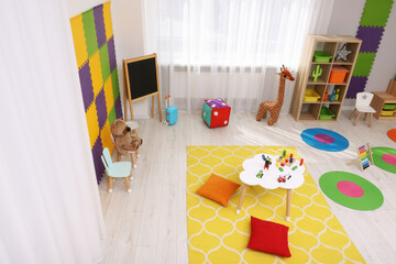Child`s playroom with different toys and furniture, above view. Cozy kindergarten interior