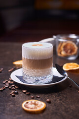 latte in a glass and coffee beans on a dark table