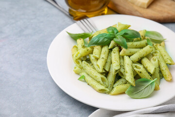 Delicious pasta with pesto sauce and basil on light grey table, closeup. Space for text