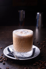 latte in a glass and coffee beans on a dark table