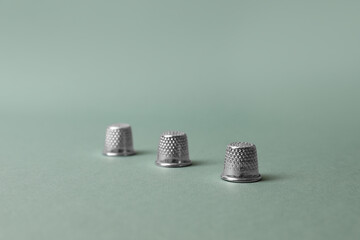 Three thimbles on pale olive background. Thimblerig game