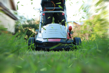 Man cutting grass with lawn mower in garden, closeup
