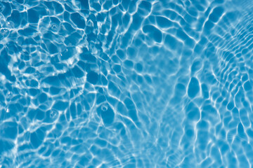 Blue water with ripples on the surface. Defocus blurred transparent blue colored clear calm water surface texture with splashes and bubbles. Water waves with shining pattern texture background.