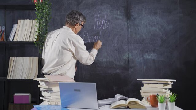 The historian man writing Benito Mussolini on the blackboard.