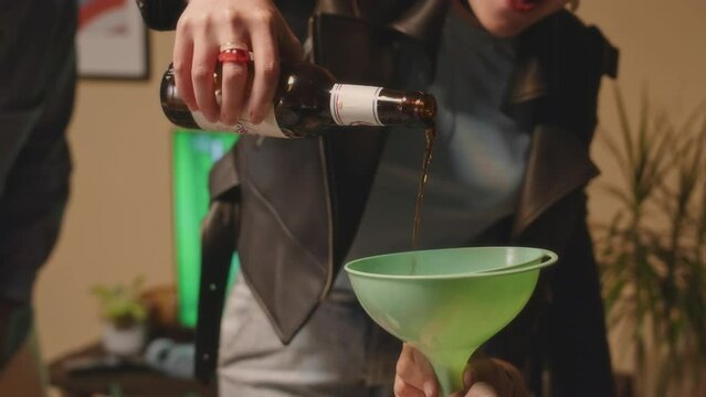 Group of cheerful multiethnic young people playing drinking games with alco while having fun together during house party at weekend