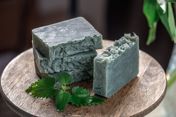 Pieces of refreshing natural handmade soap on a wooden stand with green leaves of fresh mint. Concept of organic cosmetics for skin care