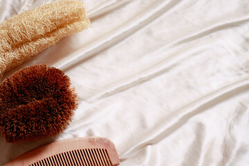 Overhead view of wooden comb, organic bristle body brush and a loofah sponge with copy space showing self care, wellness and sustainable zero waste lifestyle