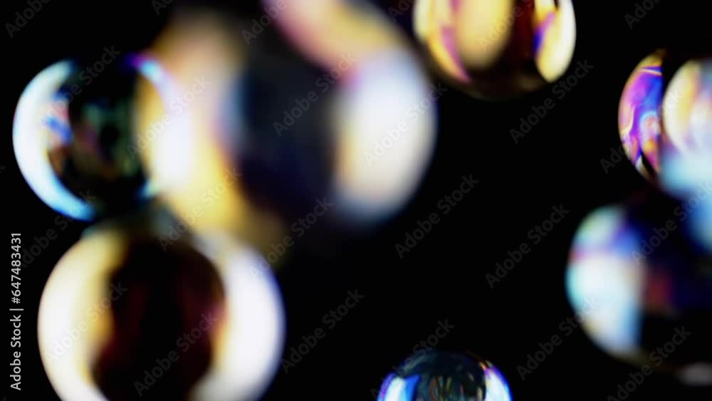 Poster lot of large colorful soap bubbles fly on a black background in empty space. blowing. falling. splas