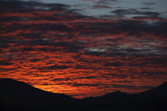 Dramatic Red Sunset Over Silhouetted Landscape; New Zealand