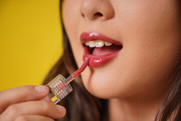 Beauty close up face portrait of asian pretty woman wearing lipstick or lip gloss. Very beautiful young girl on isolated yellow background.