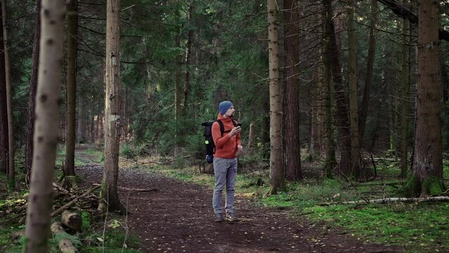 Outdoor mapping in hike. Man hiker uses smartphone to navigate in forest using an application and digital maps. Route for hiking in smart phone. Traveler guides in woods by GPS. Travel and explore. 