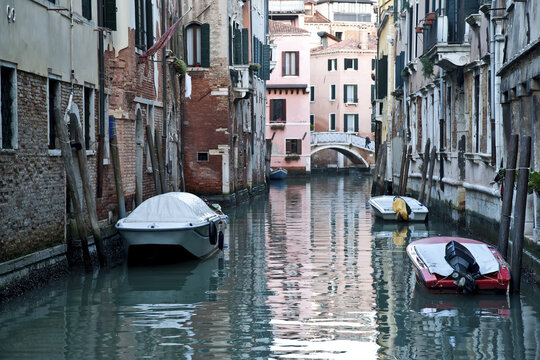 Boats Moored Along Buildings In A Tranquil Canal; Venice, Italy