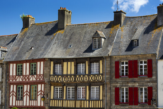 Close Up Of Colourfully Painted Half Timbered Stone Buildings And Shutters With Blue Sky And Clouds; Treguier, Brittany, France