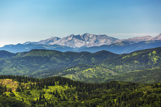Viewpoint Of Rolling Foothills With Mountain Range In Background And Blue Sky; Kananaskis Country, Alberta, Canada