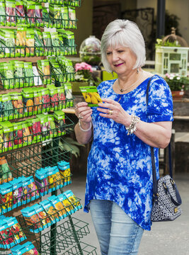 Mature Woman Shopping For Garden Seeds In A Garden Centre In A Shopping Complex; St. Albert, Alberta, Canada