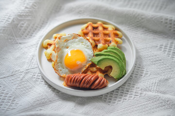 Breakfast waffles, fried eggs, sausage and avocado