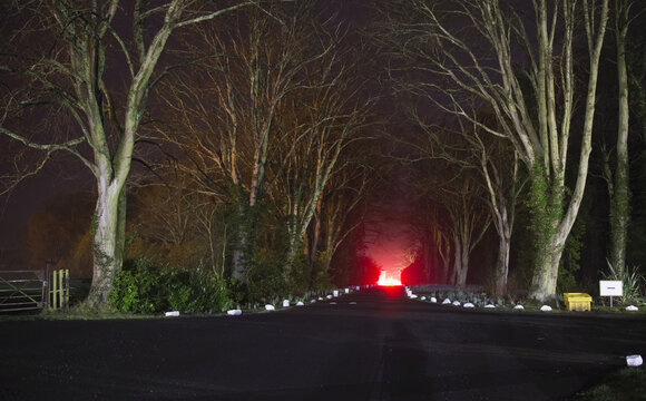 Red Light, Smoke And Flames Glowing At The End Of A Driveway; Doxford, England